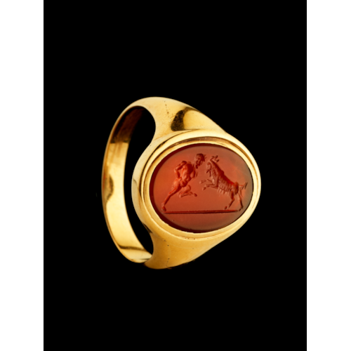 A 18k signet ring set with a Grand Tour carnelian intaglio. Pan fighting a goat.